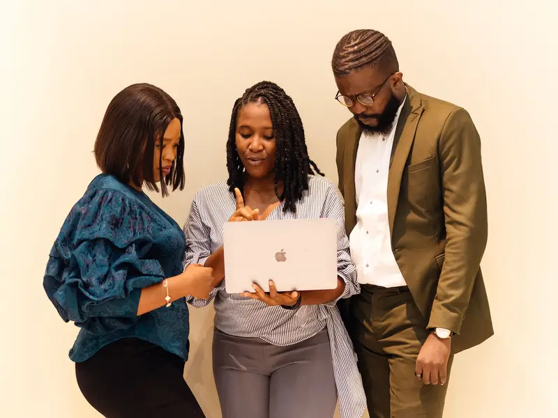 Three colleagues reviewing work together on a laptop